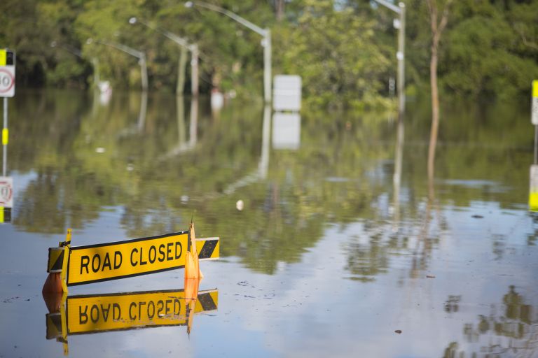 Grants road sign under water due to flooding