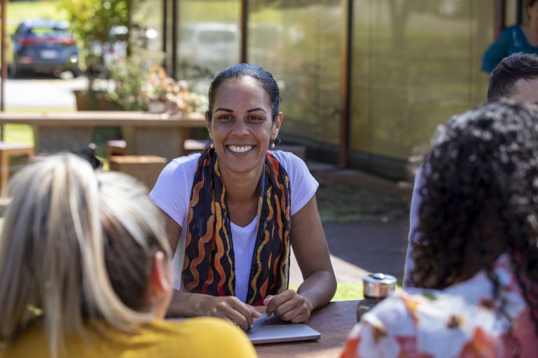 A woman smiling at two people opposite her.