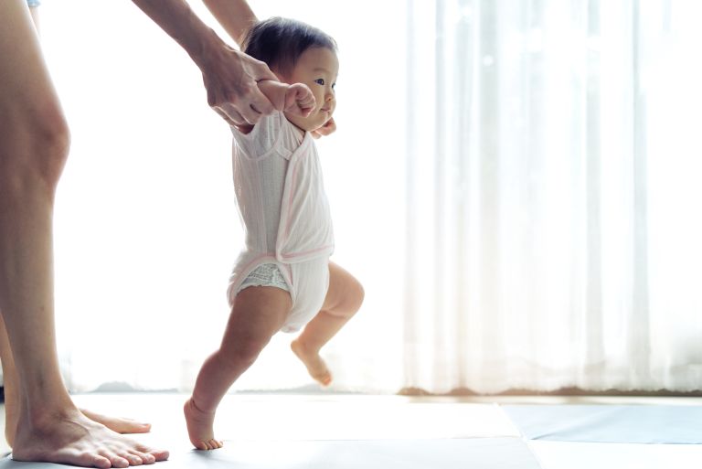 A baby walking while being held by parent