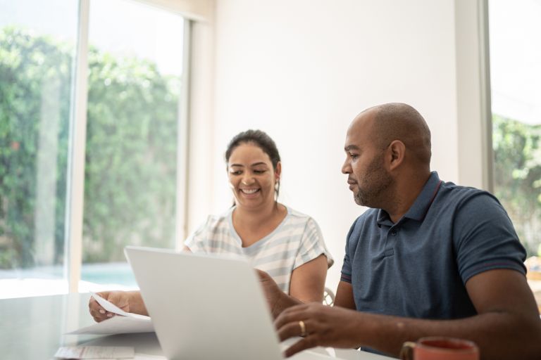 A couple sitting at a table inside using a laptop