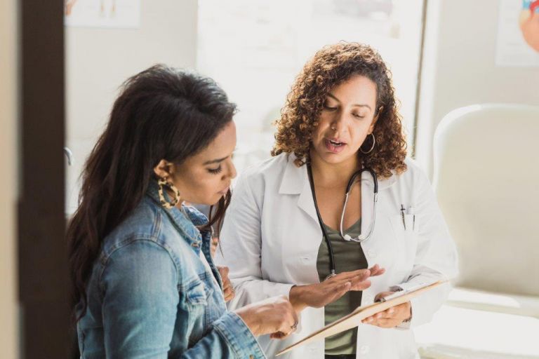 Doctor and young woman talking about information on the doctor's clipboard