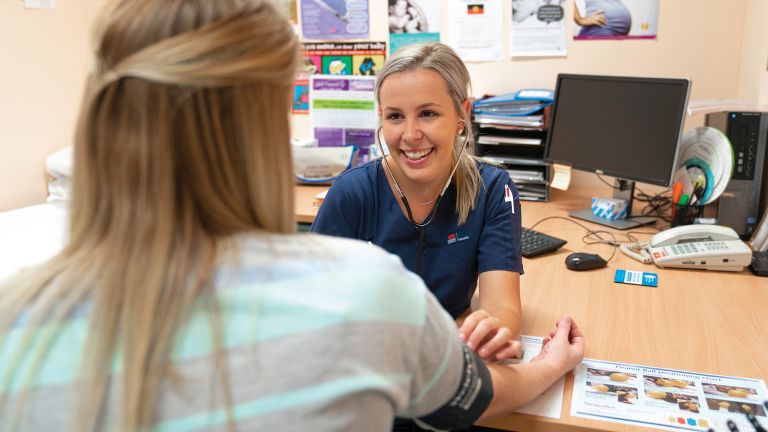 A nurse takes a woman's blood pressure