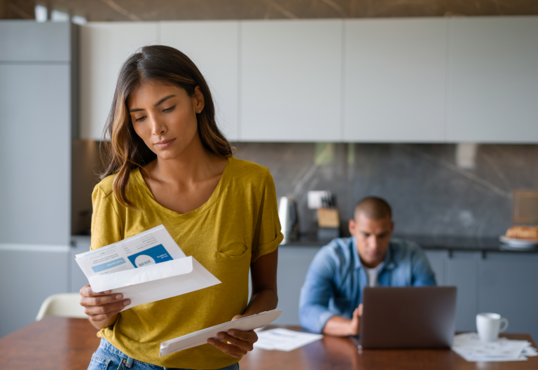 Woman looking at bill with man in background