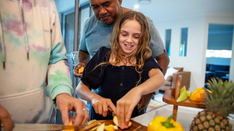 Young girl and her grandfather preparing a fruit salad