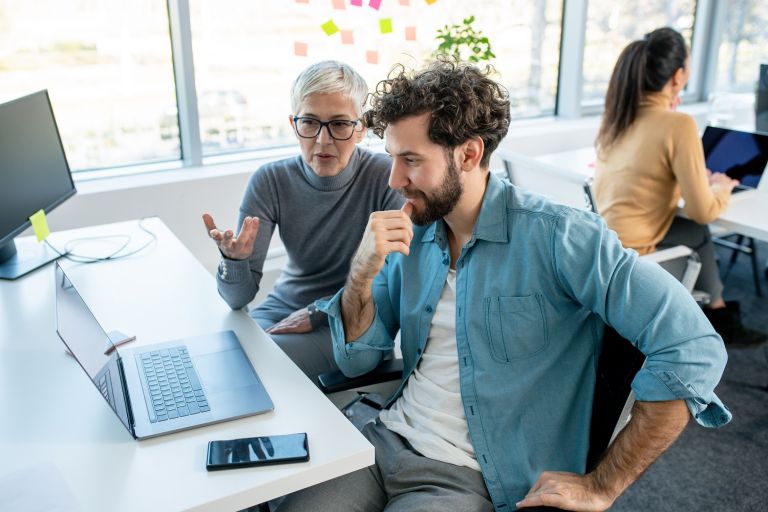 Image of lady and man in a workspace looking at a computer