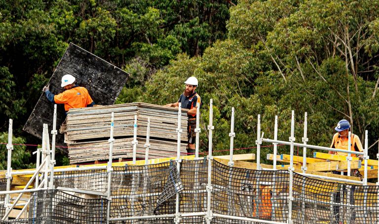 3 men in safety gear handling building materials on a construction site