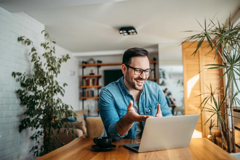 Man seated at a table working on laptop. 