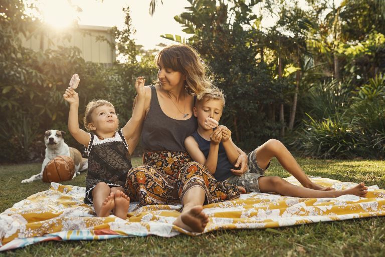 Single mother in the garden as the sun sets with son and daughter smiling