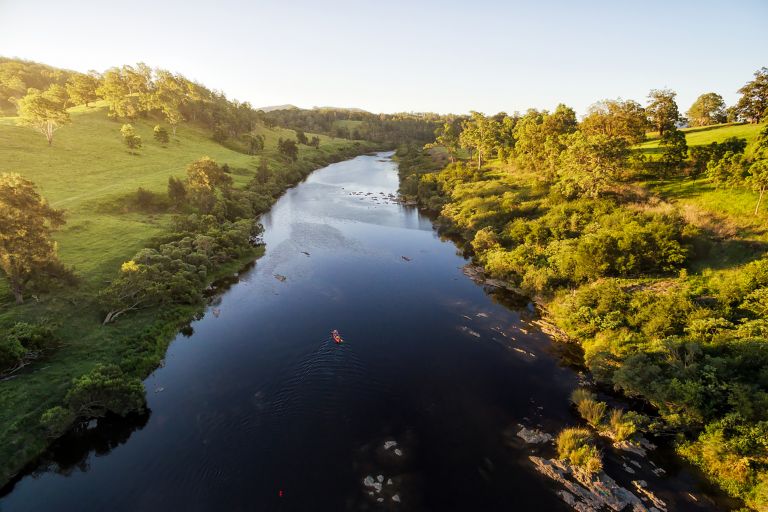 A bridge view of Hinterland River early morning, lush green riverbank on each side