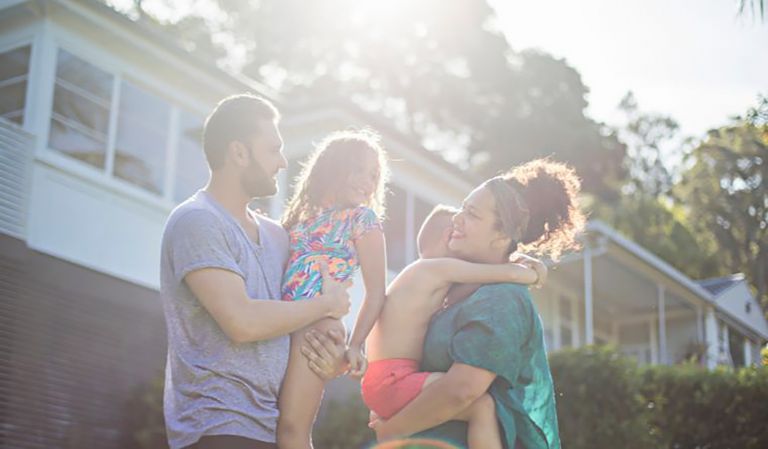 Family of 4 outside their new home in the morning sun 