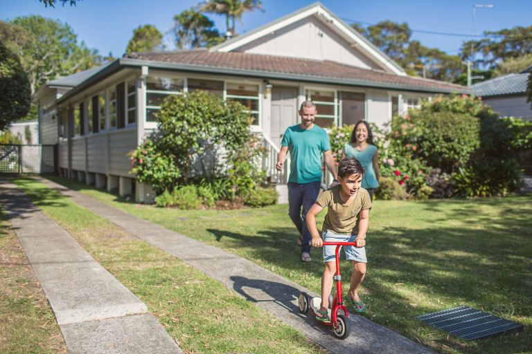 Parents outside home watching child on scooter