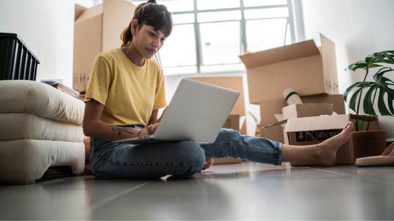 Girl with a laptop surrounded by boxes