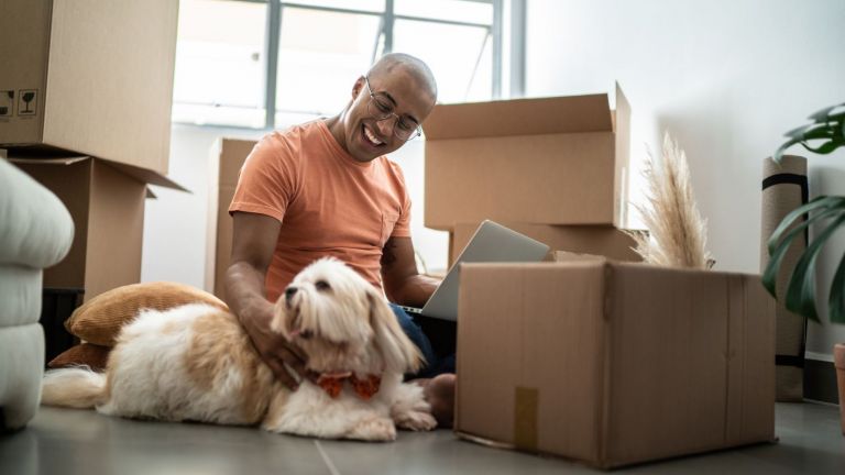 Man unpacking boxes also pats his dog