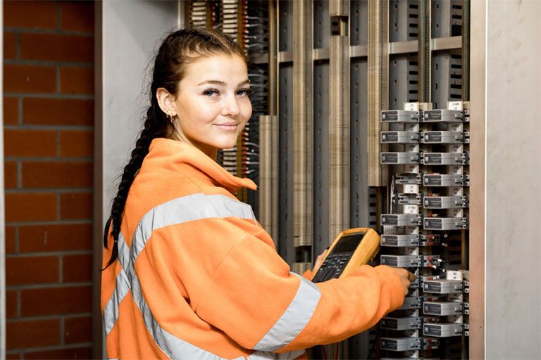 Female VET apprentice electrician working on power board. 