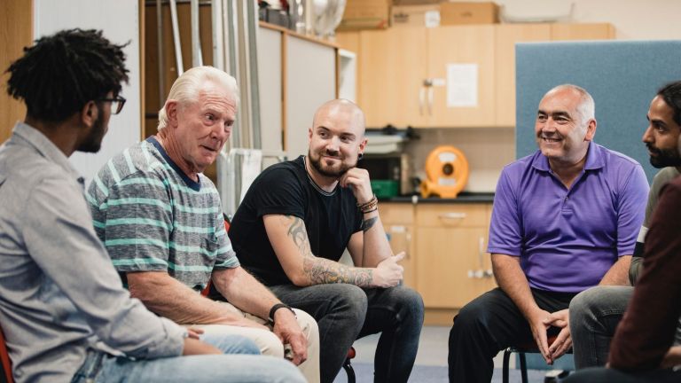 A group of men inside a community centre talk to each other