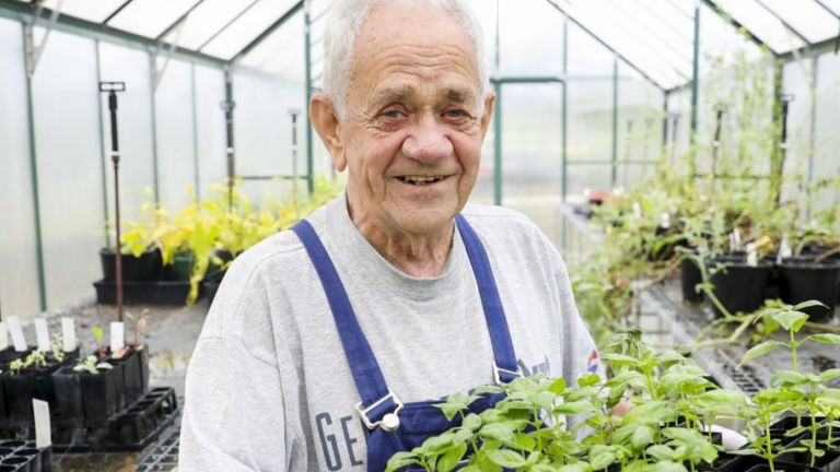 A man surrounded by plants inside a garden centre