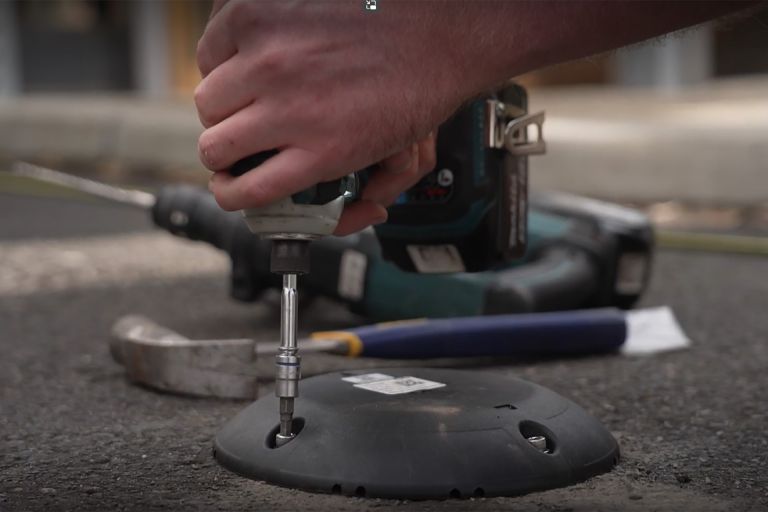 A person drills equipment into the ground for the Smart Digital Kerbside project.