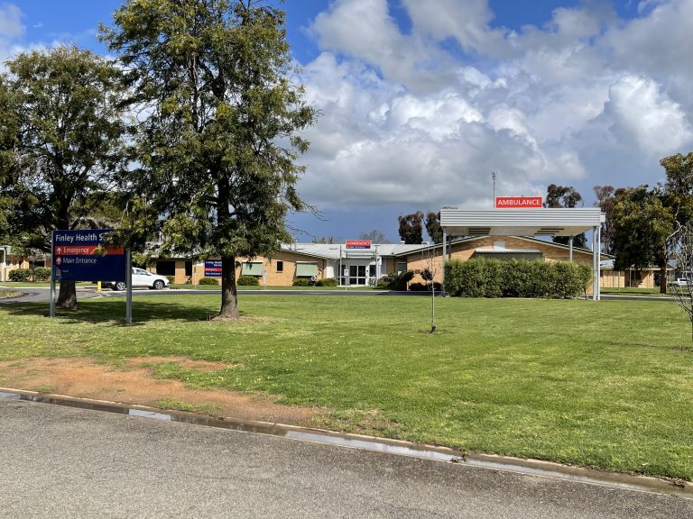 Main entry to the Finley Hospital. A sign indicating the main and emergency entry points is on the left side of the image.