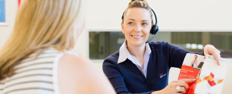 Hospital receptionist showing a visitor a brochure