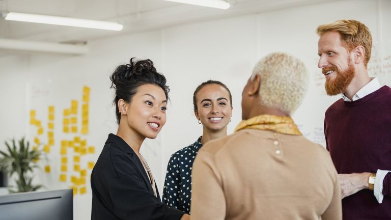 Colleagues standing in a small group discussing something while working at an office