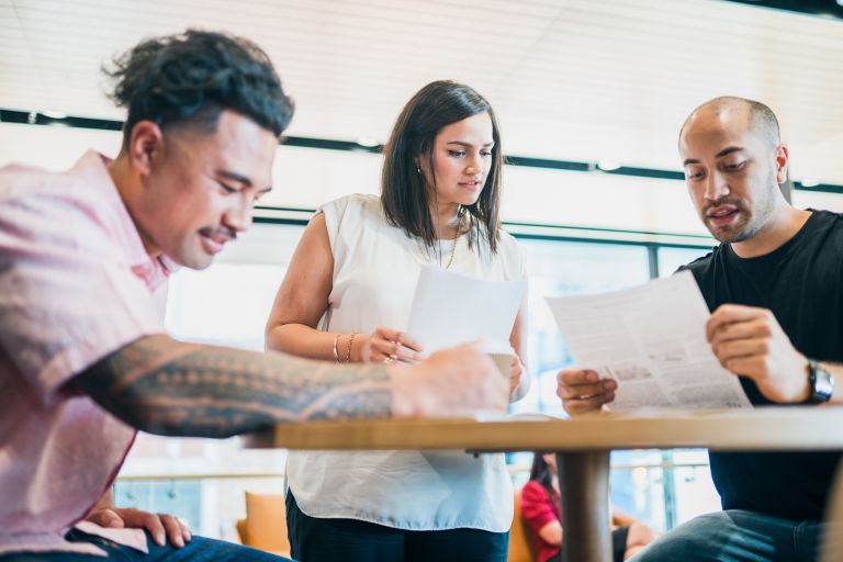 A small business meeting with three people talking over a table.