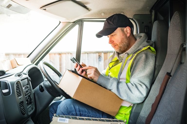 Man working second job as a delivery driver in a van with parcels on seat