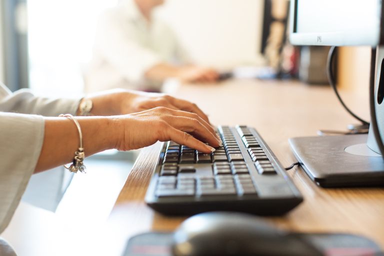 Close-up of a woman's hands typing on a computer keyboard