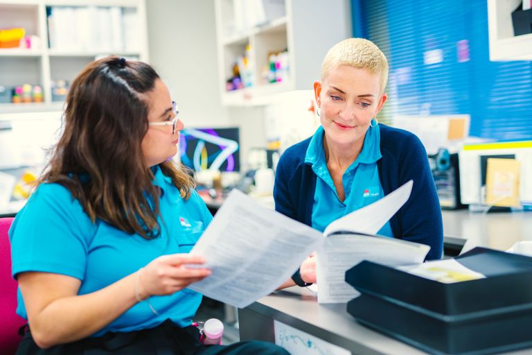 Two female health care workers looking at paperwork together. 