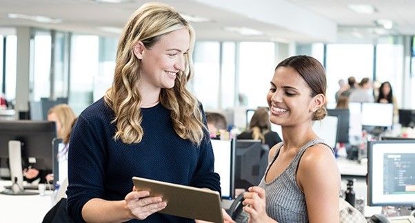 Two women smiling and looking at a tablet.