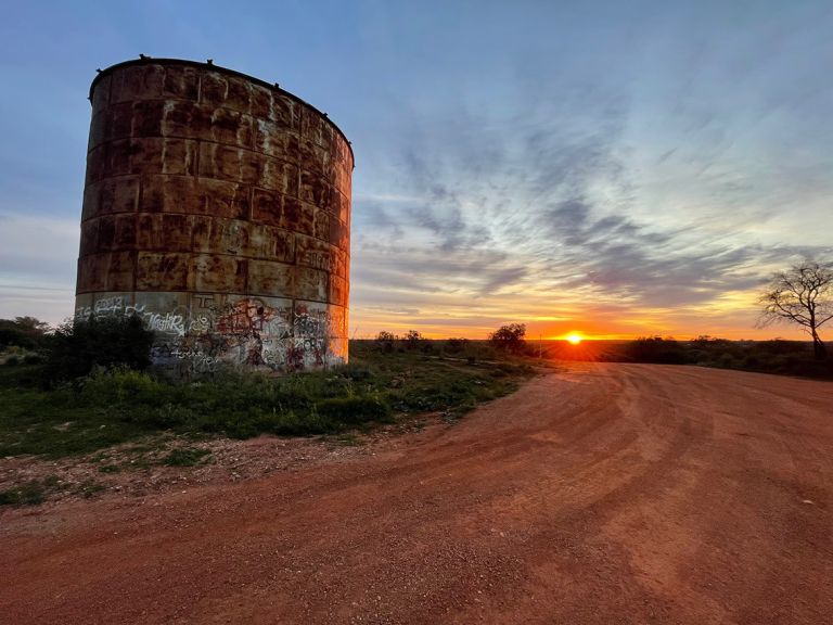 An image of an old, graffitied silo at sunset.