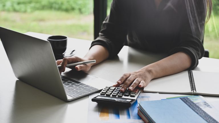 Woman's hands at laptop with calculator