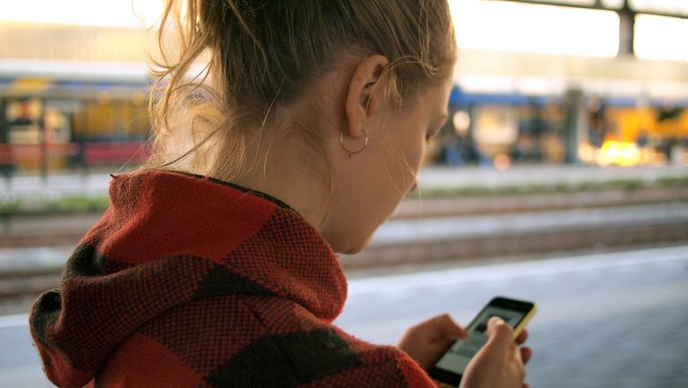 Close up of teen from behind, using their phone.