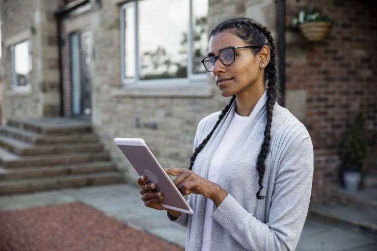 A woman using a tablet and looking off into the distance.