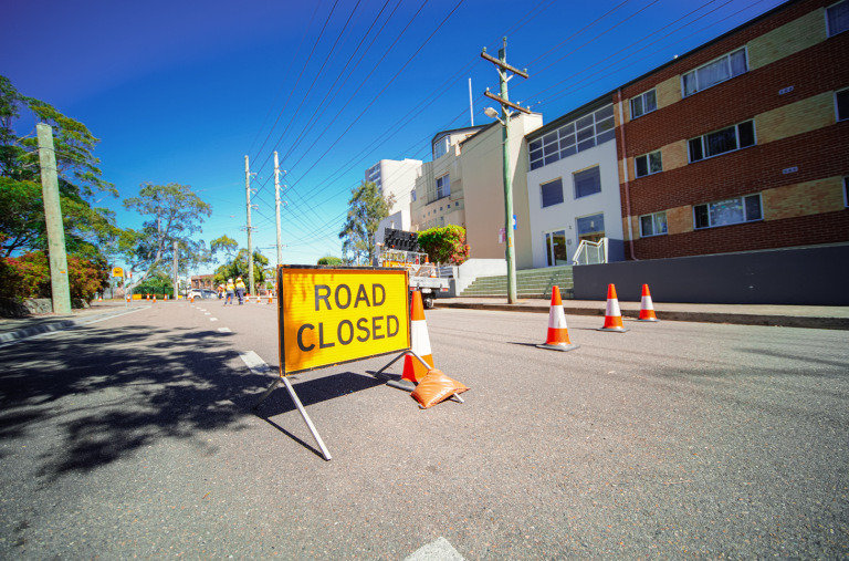 Road closed sign with traffic cones in the middle of a road.