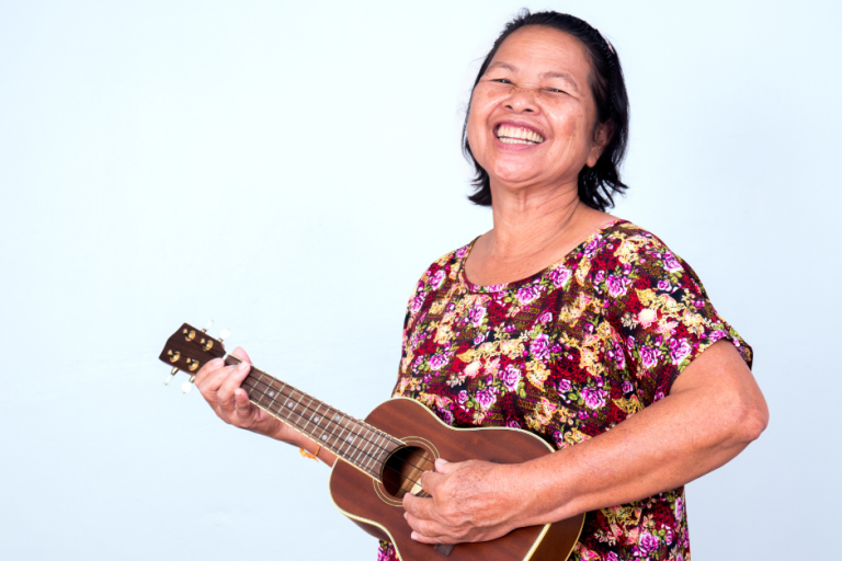 woman smiling to camera, playing ukulele