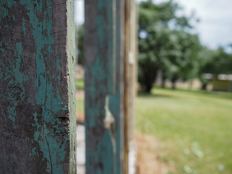 View through wall frame with peeled paint onto field