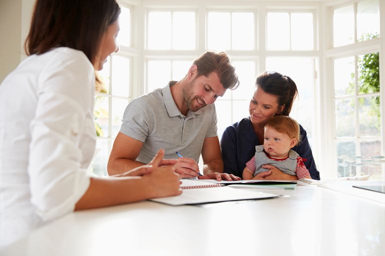 Mother and father with a baby signing a document