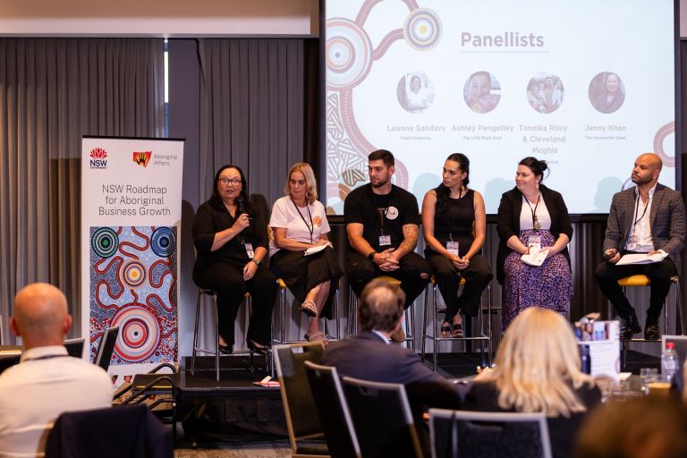 A panel of speakers on a stage talking at an Aboriginal business conference