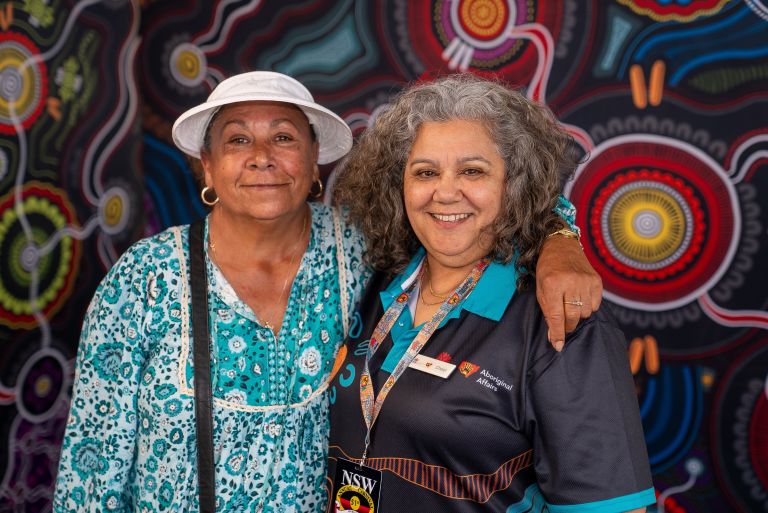 Two Aboriginal women standing side by side smiling