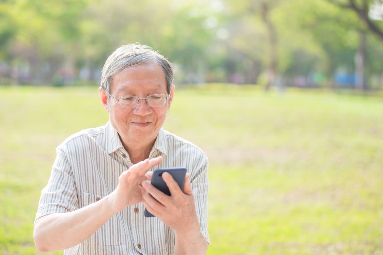 Older gentlemen of Asian decent holding a phone and scrolling