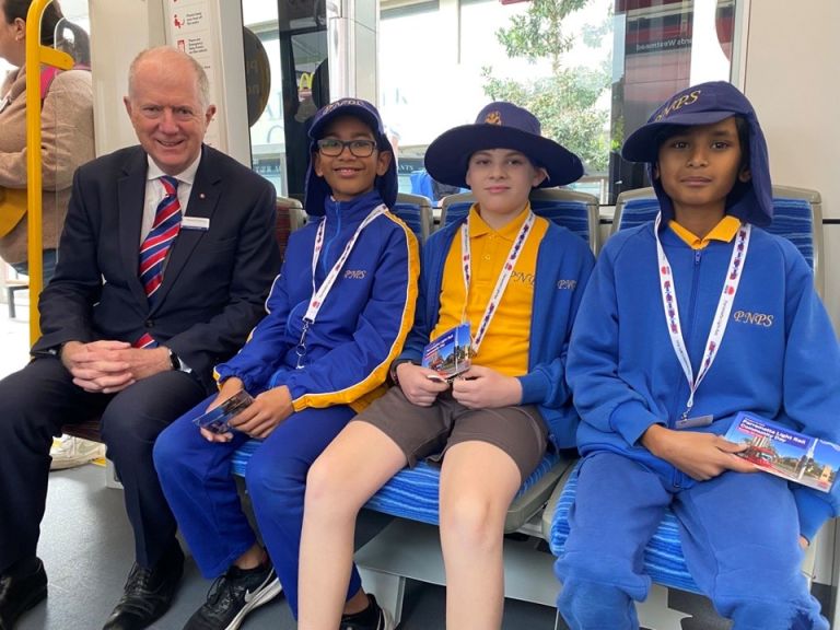 school students seated next to Howard Collins on light rail vehicle