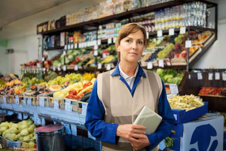 Female worker standing in a fresh produce supermarket.