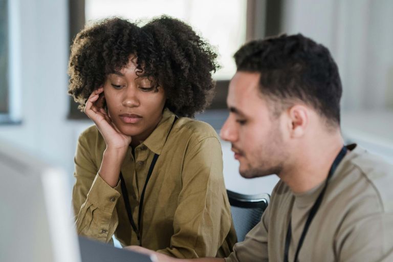 A male and female sitting looking at a laptop computer.