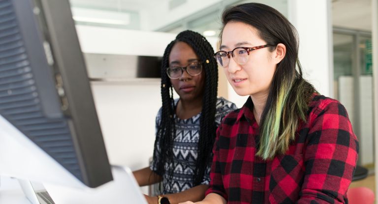 Two women looking at desktop computer screen