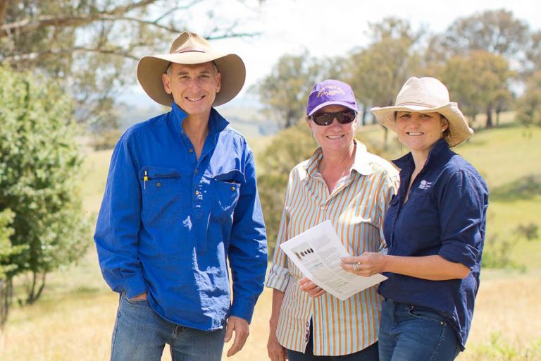 3 people smiling at the camera in the sun with a rural bush background