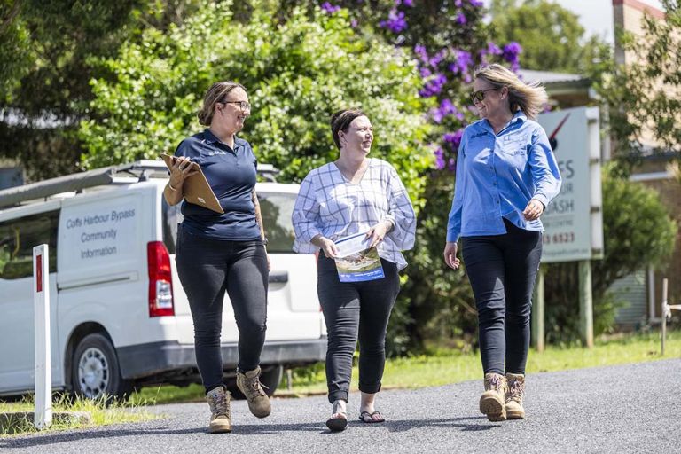 Three people walking down a quiet road having a conversation.