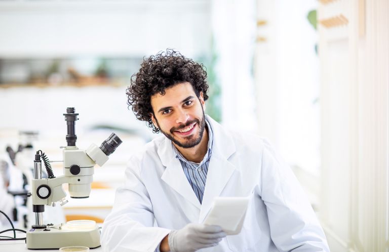 male researcher in laboratory next to microscope