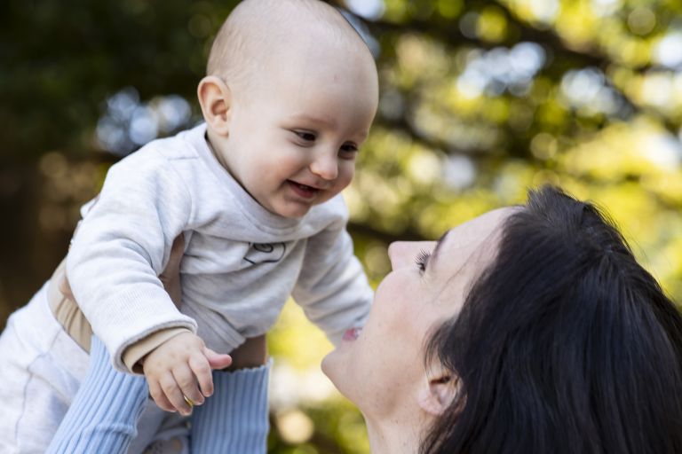 Mother holding baby up in park