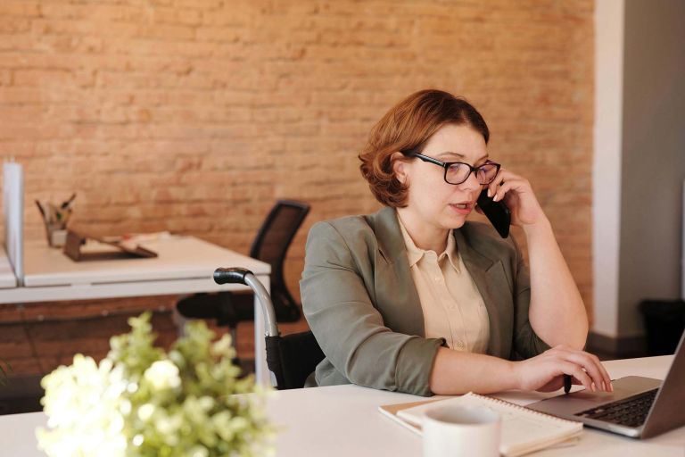 Female office worker sitting at a desk while talking on the phone. 