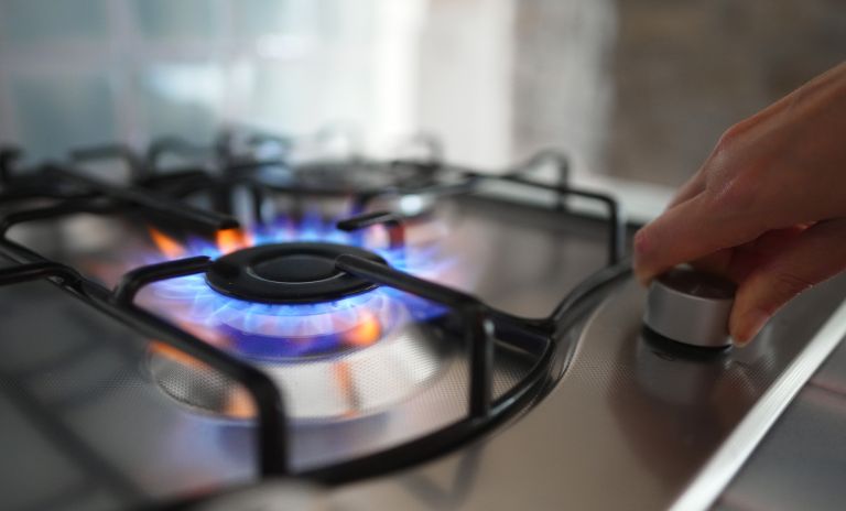 Hand turning on gas cooker with flame